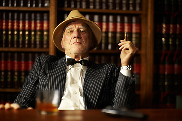 Image showing Portrait, mafia and boss with cigarette in office for habit, smoking or relaxing by desk. Mature, mob leader and retro fashion in suit, bowtie and hat for crime, danger or power with vintage look