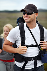 Image showing Man with smile, backpack and woman on hiking adventure in mountain holiday with nature, freedom or wellness. Travel, trekking and happy couple walking on natural outdoor journey together on vacation.