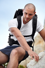 Image showing Man on rock, backpack and climbing on hiking adventure in mountain with nature hike, freedom or wellness. Travel, trekking and person in countryside, natural outdoor journey and hanging on cliff.