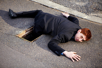 Image showing Portrait, accident and an unlucky business man on a street in the city after falling into a hole. Mistake, stuck or clumsy and a ginger corporate professional on the road in a suit with a problem