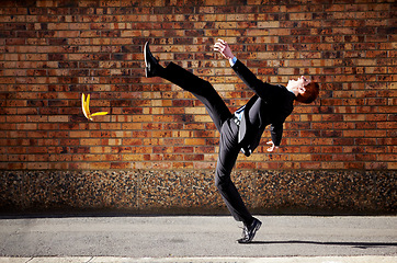 Image showing Accident, slip and banana peel with a business man in the city, falling by mistake on a street. Walking, step and unlucky with a young professional employee in an urban town for his commute to work