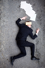 Image showing Death, accident and brick on a business man lying on a street in the city from above for financial crisis. Ground, documents and mistake with a young employee crippled by debt in a recession