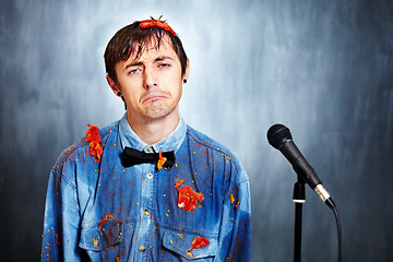 Image showing Portrait, sad and a man comic in tomato with a microphone after a bad performance at a comedy club. Depression, fail or boo with an unhappy young comedian in studio on a gray background for a show