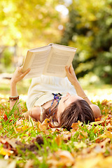 Image showing Reading, book and woman relax in park with novel in nature learning for education as student outdoor on campus. University, college and young person with textbook on grass field for scholarship