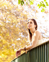 Image showing Woman, thinking or park by fence in nature on holiday vacation in countryside, autumn or France, Garden, view or calm female person with peace outdoors for fresh air, wellness or break to relax