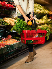 Image showing Woman, hands and shopping basket at supermarket with healthy food, vegetables and nutrition wellness. Customer, choice or grocery store for retail in fruit, natural diet and vegan groceries on shelf