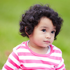 Image showing Girl, toddler and face for outside, grass or park for child development. Adorable kid, curly hair and alone in pink clothes with expression for curiosity on field in garden with backyard for playing