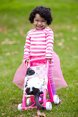 Image showing Portrait, happy kid and kitten for playing with baby carriage on grass, garden or backyard of family home. Little girl, pet and pushing of stroller together for fun, imagine or game for bond by care