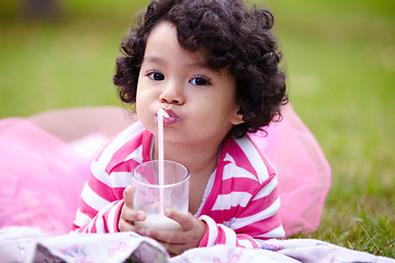 Image showing Portrait, child and glass of milk on grass while lying down with satisfaction on face for beverage. Little girl, pink tutu and curly hair for development for health, nutrition and calcium for growth