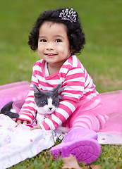 Image showing Nature, crown and girl with kitten in a garden on grass on a summer weekend together. Happy, sunshine and portrait of child with tiara sitting and having fun with cat, animal or pet on lawn in field.
