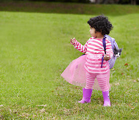 Image showing Nature, kitten and girl child with backpack walking on grass in outdoor garden in summer. Confused, backyard and young kid with childhood playing on the lawn with cat in field or park in countryside.