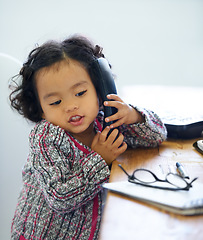 Image showing Playing, talking and a child on a telephone for communication, pretend work and cute. Sitting, house and a girl, kid or a baby speaking on a landline phone for play, imagination or discussion
