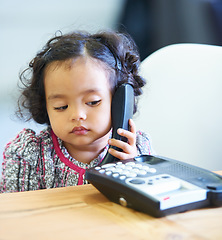 Image showing Listening, talking and a child on a telephone phone call for communication in a house. Home, contact and a girl, kid or baby speaking on a landline for conversation, play or a discussion at a desk