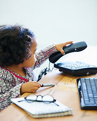 Image showing Playing, child and a telephone for a phone call at a desk for communication, pretend work or childhood. Playful, table and a girl, kid or baby with a landline for conversation, contact or secretary