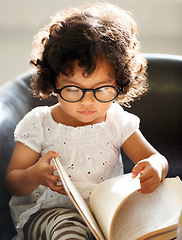 Image showing Baby, sofa and a child reading a book for education, learning and knowledge in a house. Morning, smart and a girl, kid or toddler with a story and glasses for studying or childhood on the couch