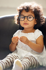 Image showing Girl, child and portrait or glasses for play, learning development or education growth. Female person, toddler and face eyewear on sofa in home for comedy outfit as professional, intelligence or fun