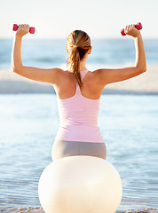 Image showing Woman, pilates ball and sitting with dumbbell for fitness on beach, fresh air or peace. Female instructor, stretching or balance in back view for health, wellness or zen for meditation for outdoors