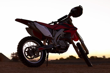 Image showing Dirt, bike and sunset in desert for action danger competition, fast race or speed training. Off road, motorcycle and helmet outdoor for fearless brave adventure, adrenaline or extreme sport transport