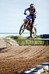 Image showing Person, motorcycle or bike jump on race track as professional in action competition, fearless or dust path. Rider, off road transportation for fast speed adventure or rally, extreme sport or gear