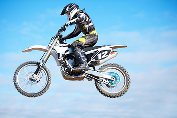 Image showing Person, motorcycle and air jump in blue sky as professional in action, competition or fearless. Bike rider, off road transportation stunt or fast speed adventure at rally, extreme sport or challenge