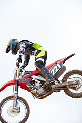 Image showing Sky, fitness and man biker jumping for stunt at competition, race or training for skill. Sports, active and male athlete on a motorcycle for energy, adrenaline or adventure with speed in nature.