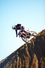 Image showing Man, motorcycle and dirt bike on hill professional rider in action danger competition, fearless or race. Male person, transportation or fast mountain adventure or blue sky, rally challenge or driving