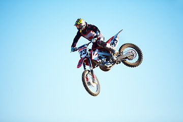 Image showing Person, motorcycle and jump adventure in blue sky as professional in action, competition or fearless. Bike rider, off road race or air stunt for speed driving at rally, extreme sport or challenge