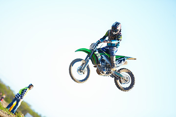 Image showing Person, motorcycle and air stunt in blue sky as professional in action, competition or fearless. Bike rider, off road transportation jump or fast speed adventure at rally, outdoor challenge or race