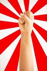 Image showing Hand in air, fist up in protest in studio isolated on a red and white background for freedom, human rights and justice, equality and sign. Arm, closeup and fight for revolution, power and violence.