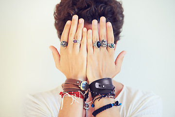 Image showing Hands, face and cover with a man in studio on a white background for fashion or style accessories. Jewelry, bracelet and rings on the fingers of a young model closeup for trendy or edgy expression