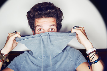 Image showing Man, fashion and hiding in studio portrait with clothes, spotlight and mystery by white background. Person, crazy and face with halo with unique trendy style, glow and jewelry for punk aesthetic