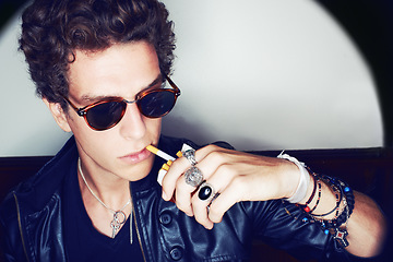Image showing Portrait of man with cigarette, rock fashion and rockstar attitude on white background in spotlight. Cool punk style, grunge and smoking, confident and handsome male model in studio with sunglasses