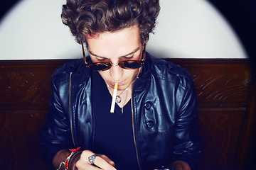 Image showing Man with cigarette, punk in sunglasses and rockstar attitude on white background with spotlight. Cool rock style, grunge fashion and smoking, confident and handsome male model in studio with freedom.