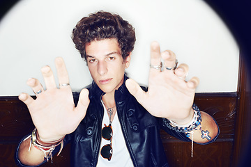 Image showing Man, spotlight and palm in portrait for fashion, jewelry and edgy rock clothes by wall background. Person, open hands and rockstar by halo with unique trendy style, glow and vintage punk aesthetic
