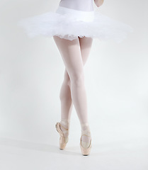 Image showing Ballet dancer, legs and pointe shoes closeup in studio white background for performance, practice or balance. Female person, feet or tutu for artistic expression training, elegant or creative workout