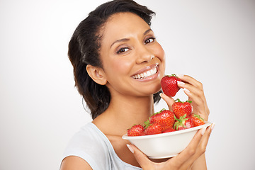 Image showing Happy, strawberries and portrait of woman in a studio for wellness, nutrition and organic diet. Smile, vitamins and young female person eating a fruit for healthy vegan snack by gray background.