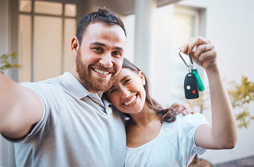 Image showing Young happy caucasian couple taking a selfie and holding the keys to their new house together. Young man taking a photo while his girlfriend shows the keys to their new home.