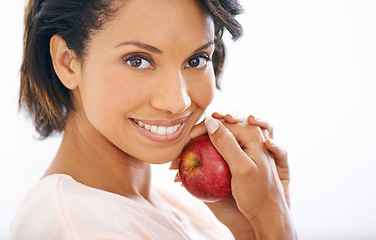 Image showing Health, apple and young woman in a studio for wellness, nutrition and organic weight loss diet. Smile, vitamins and female person from Mexico eating a fruit for healthy vegan snack by gray background