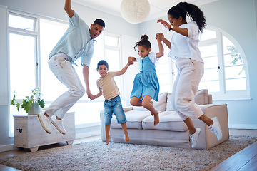 Image showing Young parents jumping and playing with their two children at home. Happy hispanic family having fun spending time together. Little boy and girl holding hands and jumping in the air with mom and dad