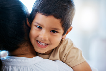 Image showing Closeup portrait of adorable little boy smiling while lying on his mothers shoulder. Mixed race mother showing her son love and affection while spending time together at home
