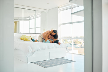 Image showing Happy playful young mixed race woman kneeling on top of her boyfriend in bed at home. Romantic couple bonding in their bedroom in the morning. Carefree boyfriend and girlfriend laughing while intimat