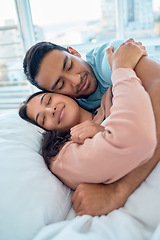 Image showing Young mixed race couple lying in bed together and cuddling early in the morning. Handsome asian man holding his beautiful hispanic wife while he sleeps at home. Feeling safe and protected in his arms