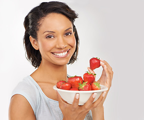 Image showing Health, strawberries and portrait of woman in a studio for wellness, nutrition and organic diet. Smile, vitamins and female person from Mexico eating fruit for healthy vegan snack by gray background.