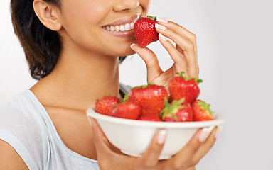 Image showing Health, strawberries and closeup of woman in a studio for wellness, nutrition and organic diet. Smile, vitamins and zoom of female person eating a fruit for healthy vegan snack by gray background.