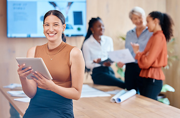 Image showing Beautiful young mixed race business woman using a tablet while leaning against the boardroom table after a meeting with her female only colleagues in the background. Our office is going digital