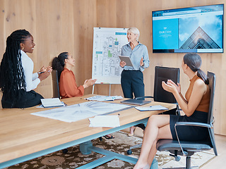 Image showing Mature caucasian businesswoman smiling and standing using a tablet while giving a presentation in the boardroom during a meeting with her female only diverse multiracial colleagues in a workplace