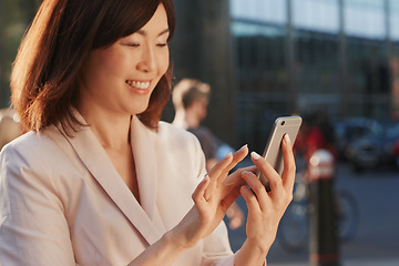 Image showing Connect with the world wherever you are. a young businesswoman using a smartphone against an urban background.