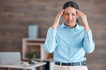 Image showing Beautiful mixed race business suffering with a headache while standing in her office. Young corporate worker struggling with a migraine while at work. The stress and anxiety of deadline pressure