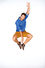 Image showing Jump, fashion and energy with a man shouting in studio on a white background for trendy hipster fashion. Success, winner and scream for motivation with a young model leaping in a clothes outfit