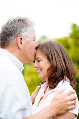 Image showing Senior man, kissing and wife on forehead in park, care and people love for commitment in marriage. France, couple and wellness in nature to connect, hug and happy together in support family on date